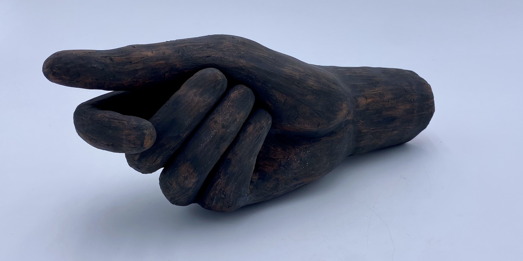 Larger-than-life ceramic hand measuring approximately 9 x 5 inches. The dark, textured surface emphasizes the organic form and expressive gesture of the piece.